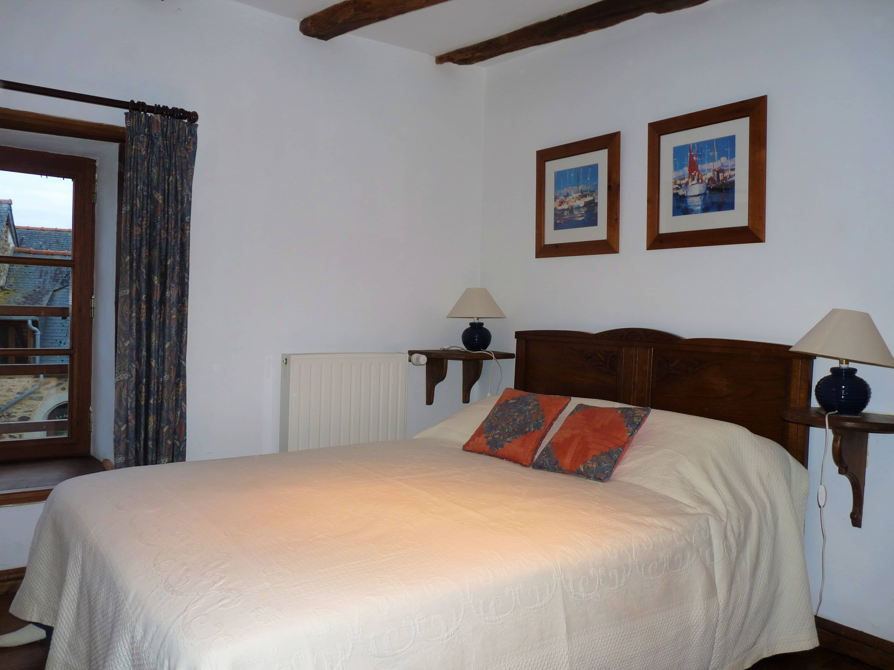 Chambre spacieuse et confortable du gîte La Julerie en Bretagne, France, avec un lit king-size, une décoration rustique élégante, une cheminée en pierre et une vue panoramique sur la campagne environnante. Parfait pour une nuit de sommeil paisible après une journée de visite de la région de Bretagne.